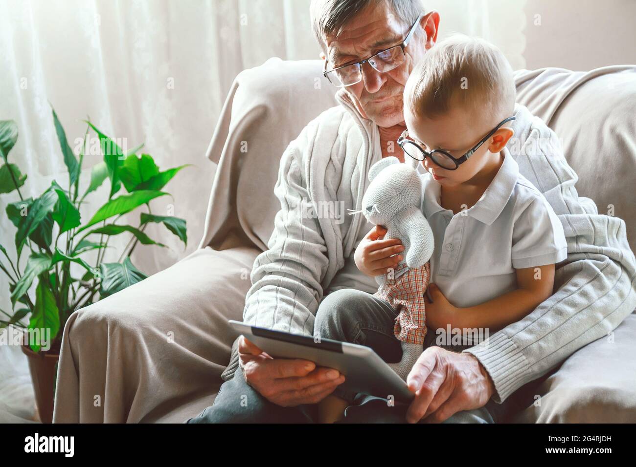 Elderly grandfather and his little grandson use a tablet device Stock Photo