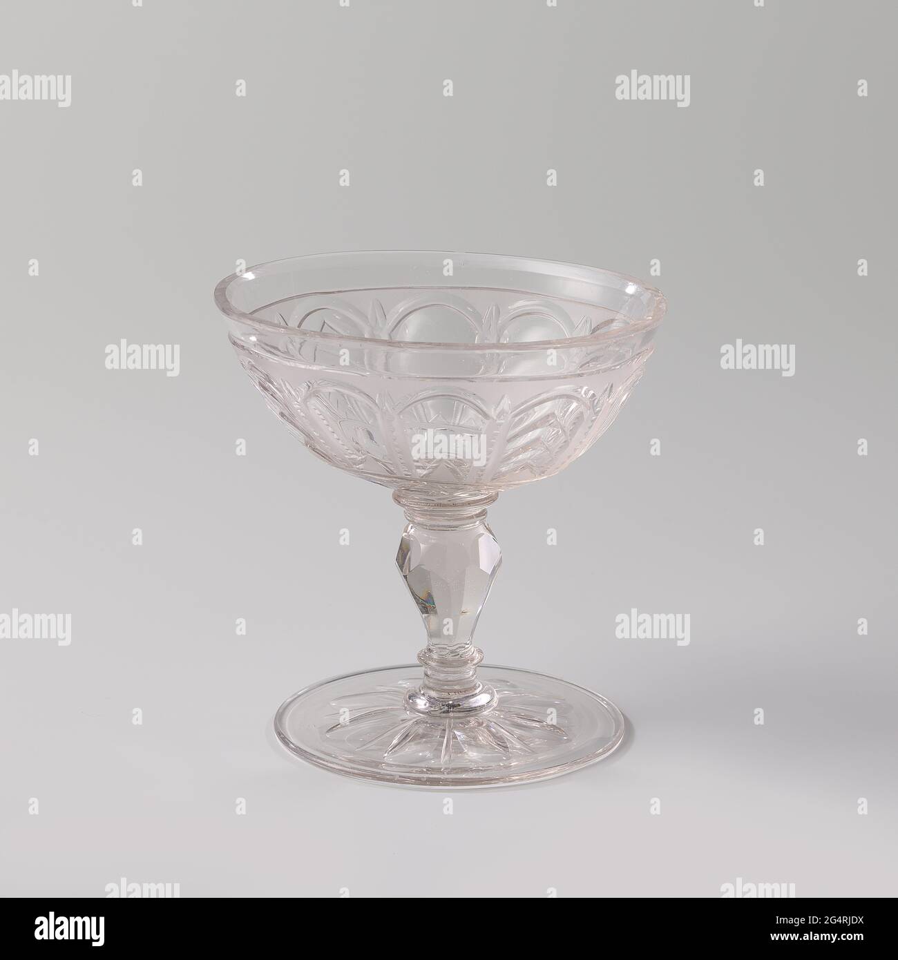 Scale on foot, with arches and stars. Flat, facet cut foot. Facet cut, baluster-shaped strain with four discs. Wide, oval chalice with facet cut bottom. On the chalice a continuous pattern of arches under a bright, cut bond with stars. This type of glass mainly served for serving sweets. Stock Photo