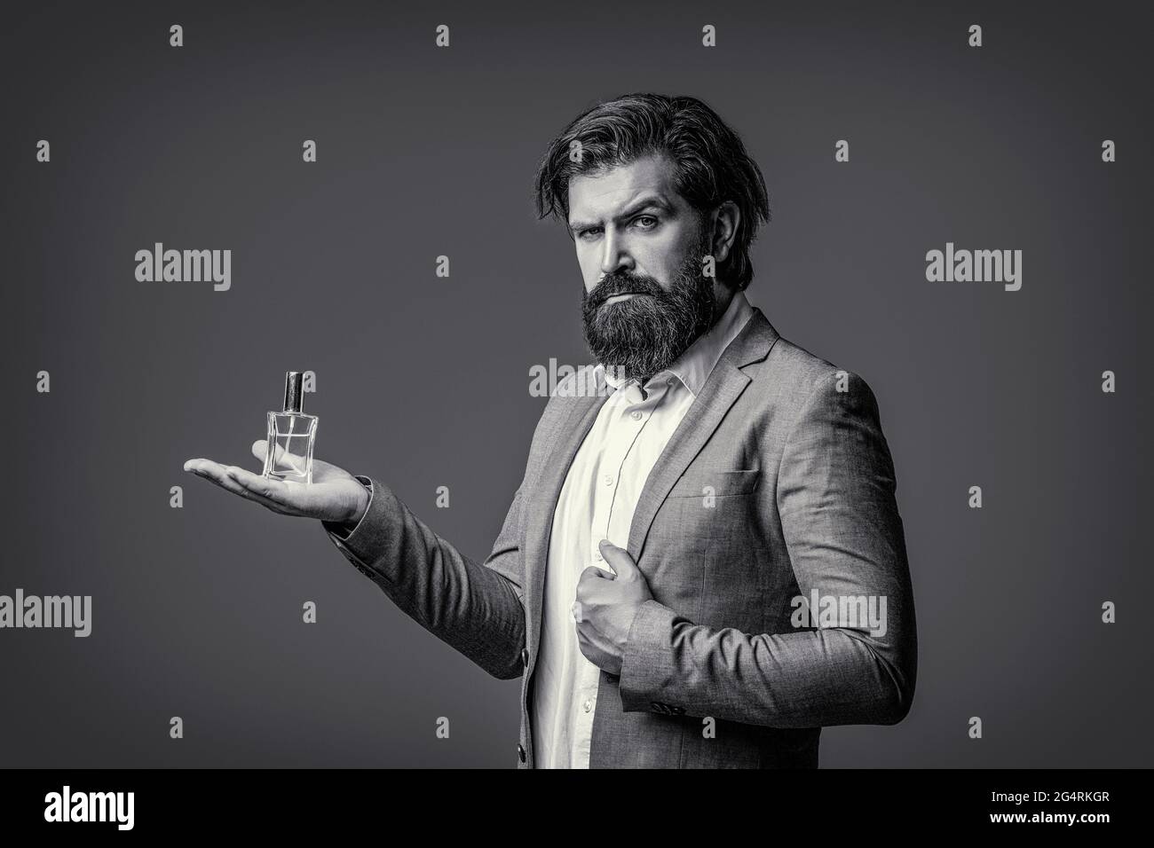 Masculine perfumery, bearded man in a suit. Male holding up bottle of perfume.  Man perfume, fragrance. Perfume or cologne bottle. Black and white Stock  Photo - Alamy