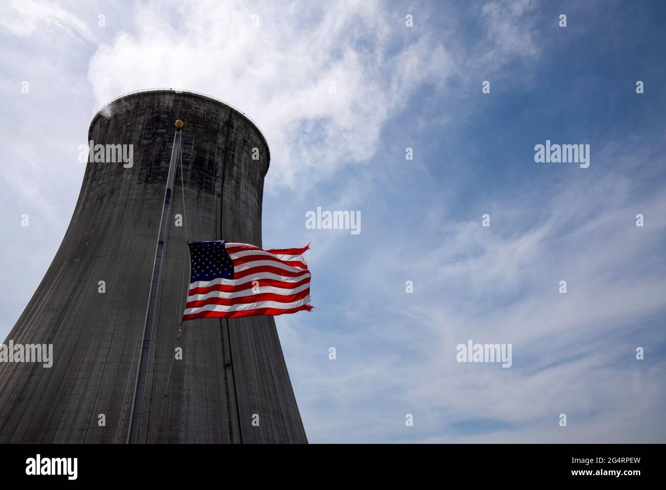 The US flag flies at half mast in front of a coalfired power plant's