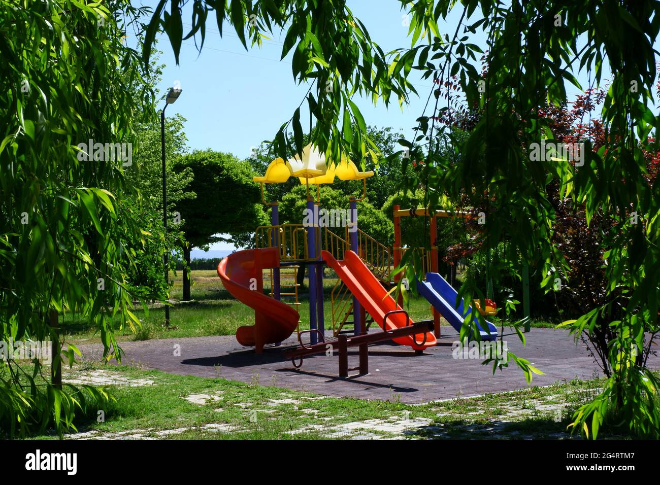 Kids' Playground outdoor within trees in a sunny day Stock Photo
