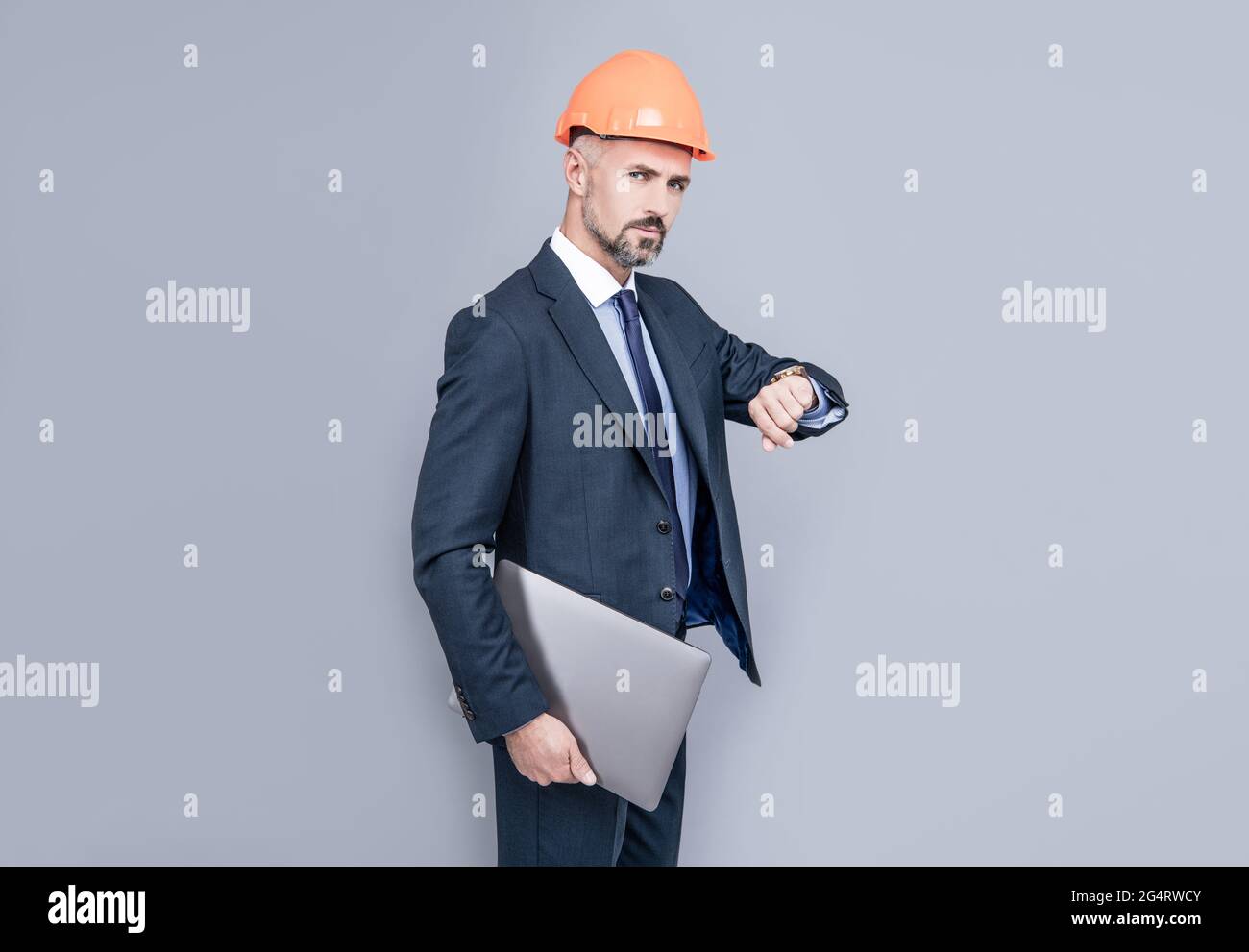 businessman man in building helmet hold laptop checking time, on schedule Stock Photo