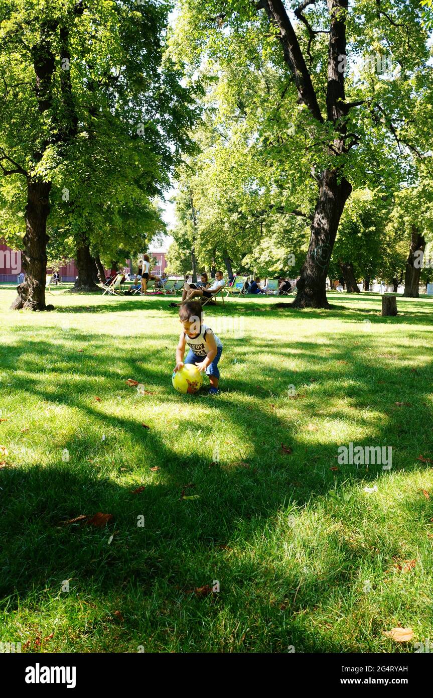 POZNAN, POLAND - Oct 20, 2015: Young toddler boy playing with a ball on green grass at a park. Stock Photo