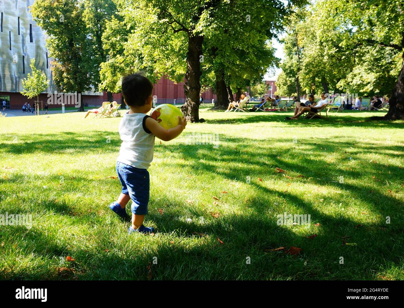 POZNAN, POLAND - Oct 20, 2015: Young toddler boy playing with a ball on green grass at a park. Stock Photo