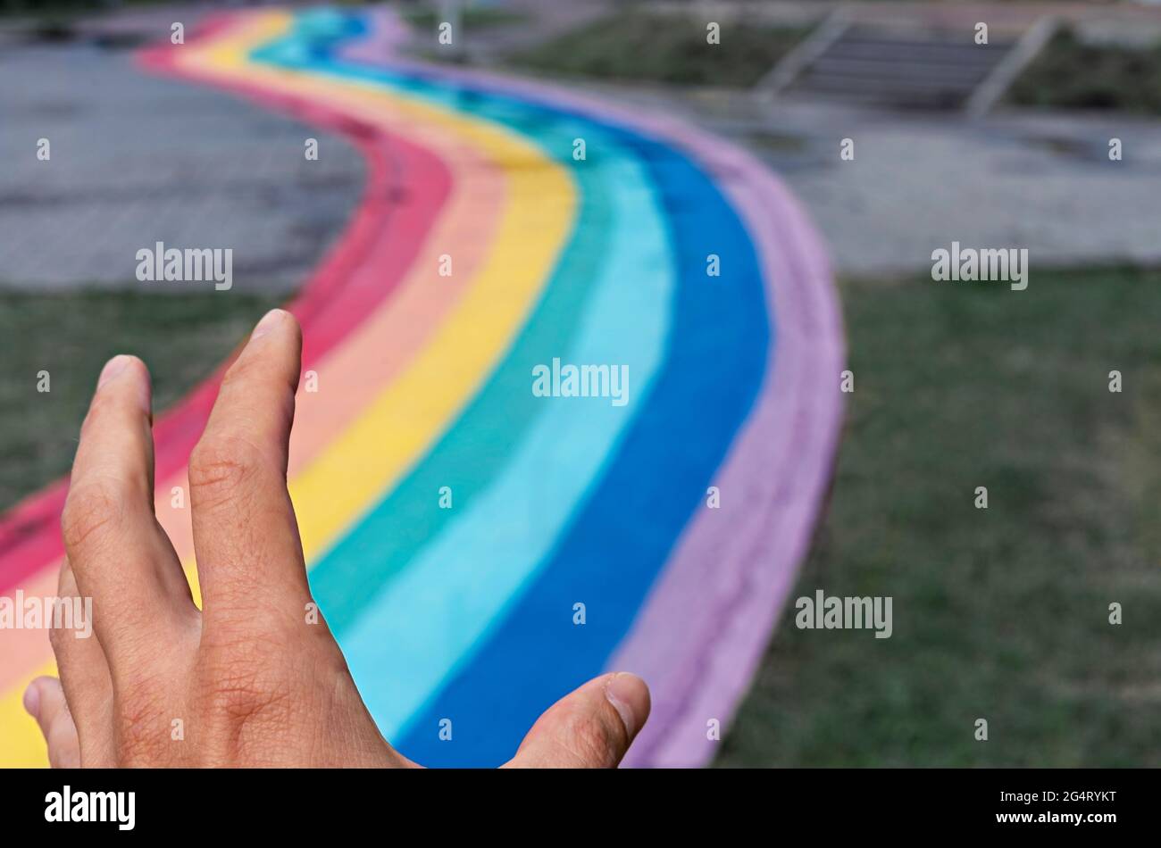 Human hand releasing rainbow winding path on city street, copy space, love, freedom and friendship, abstract selective focus, peace Stock Photo