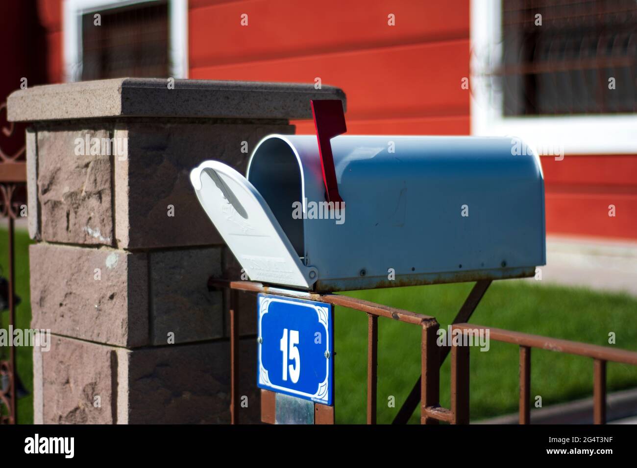 Just in front of the garden gate is an old-style mailbox with an open lid. Selective Focus Mail Box Stock Photo