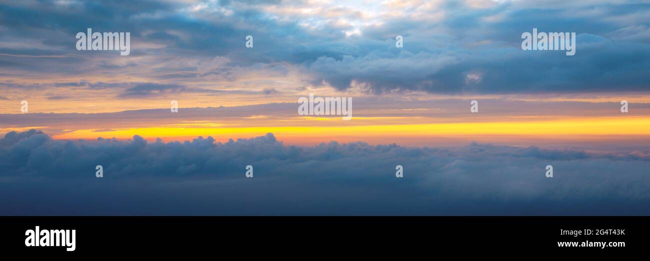Beautiful sunset sky above clouds with dramatic light. Cabin view from airplane. Flying above the clouds. view from the airplane. Beautiful blue sky b Stock Photo