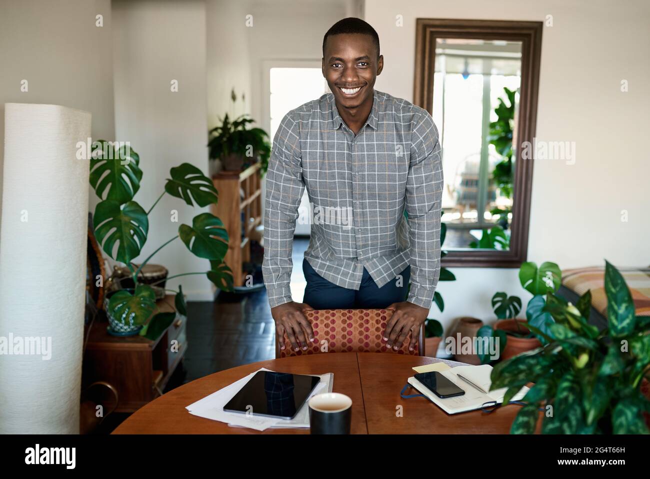 Smiling African businessman leaning on a table while working from home Stock Photo