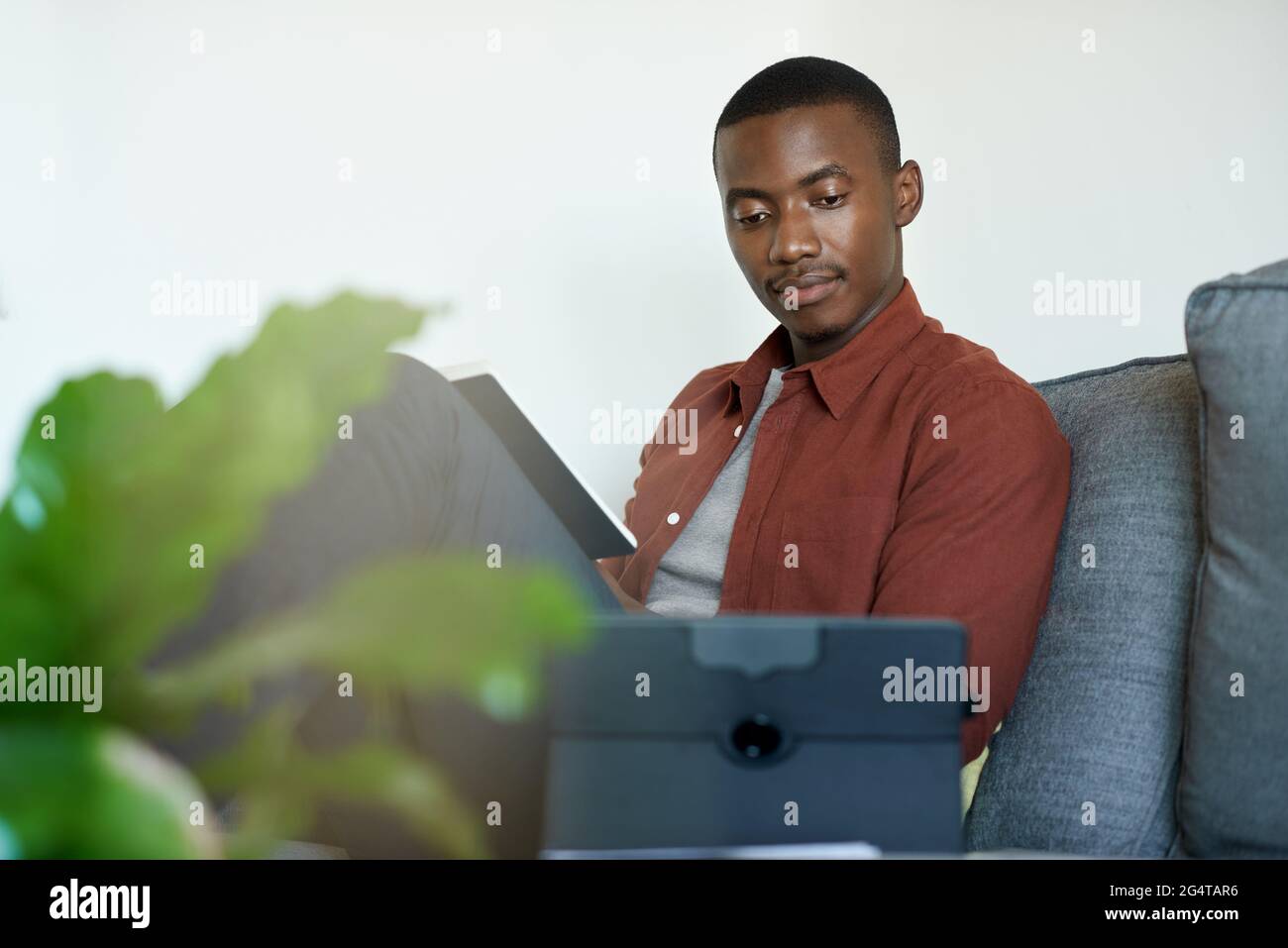 Young African man working from home using two tablets Stock Photo