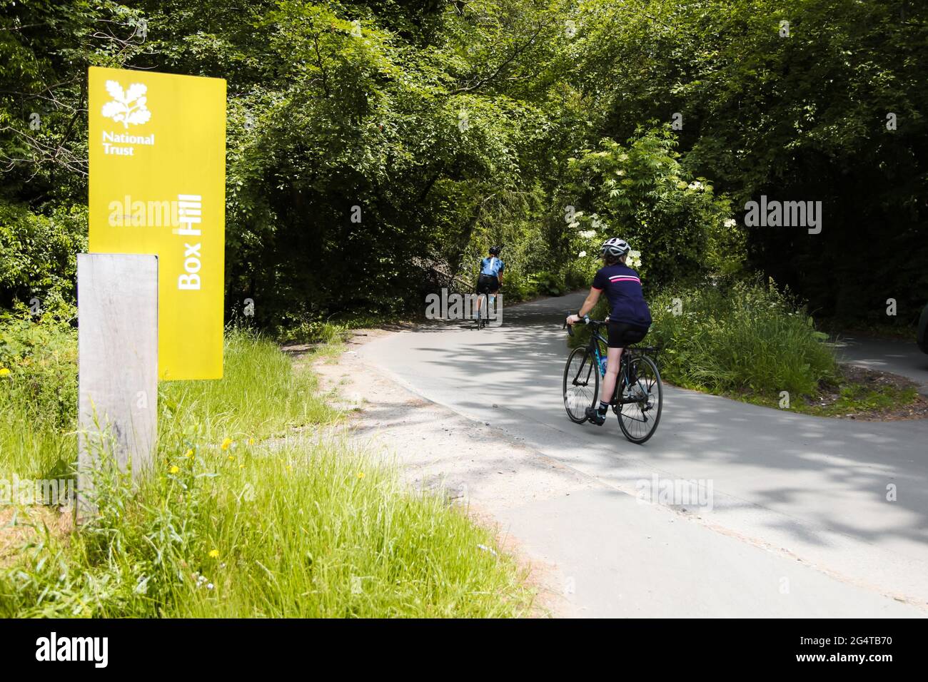 Box Hill sign with cyclists cycling at top of National Trust site