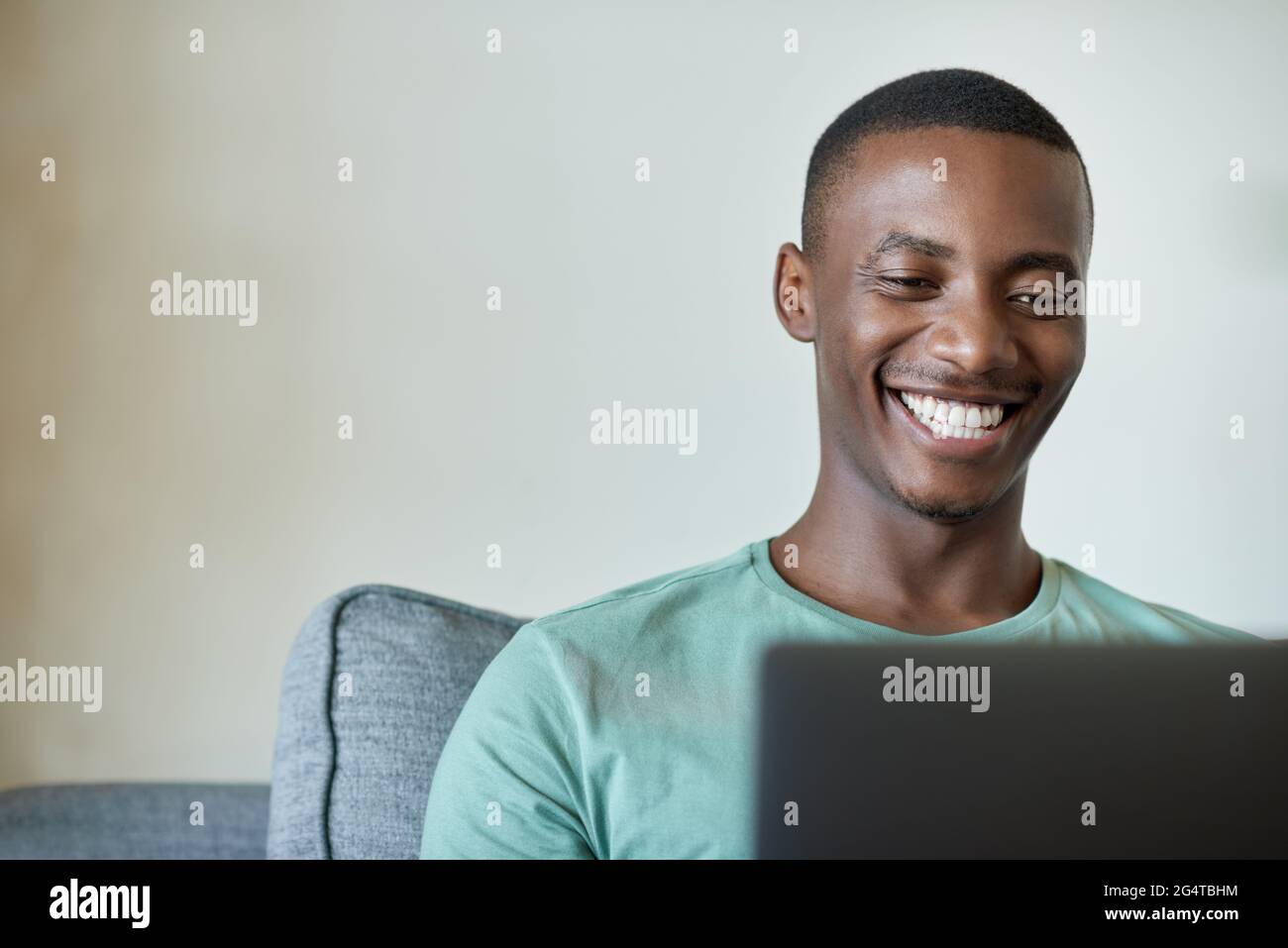 Smiling young African man working on a laptop at home Stock Photo