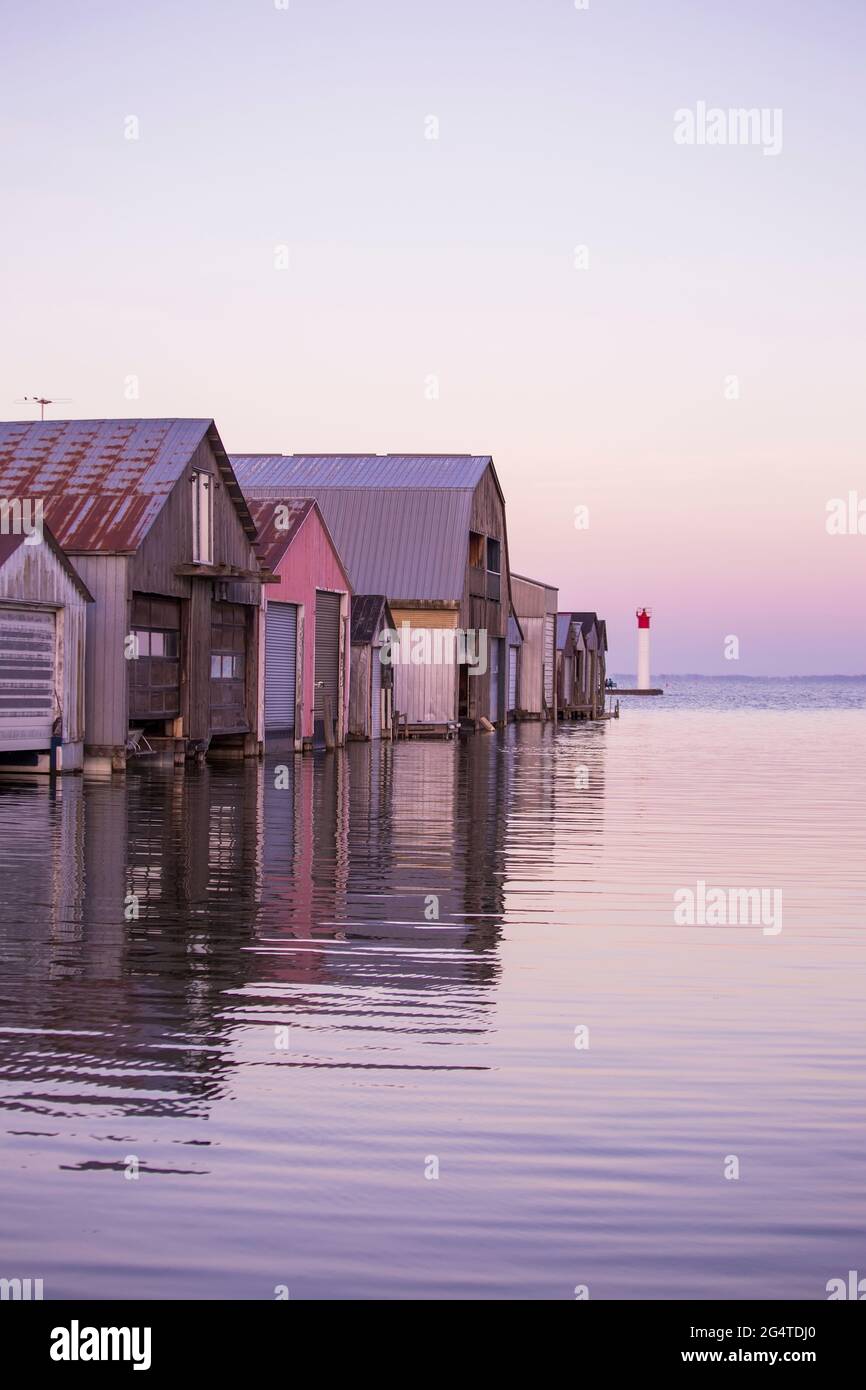 A row of Boat Houses on Calm Waters at Sunset Stock Photo