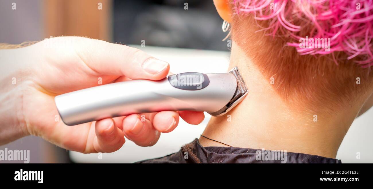 Back view of hairdresser's hand shaving nape and neck with electric