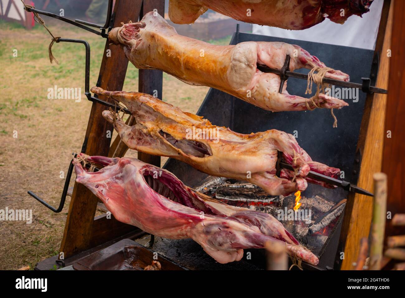 Process of cooking pork carcasses on spit at summer street food market Stock Photo
