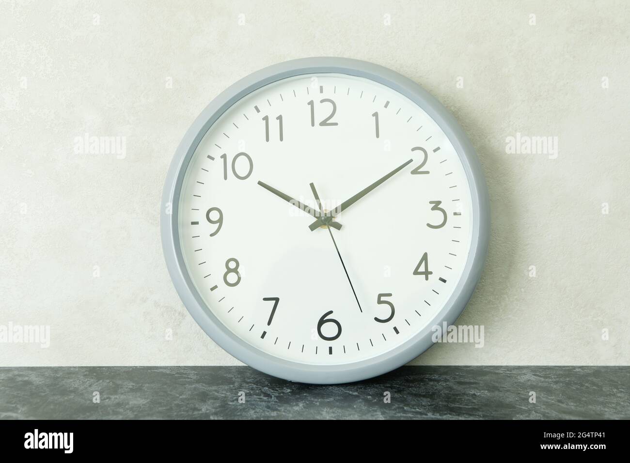 Standard gray clock against white textured background Stock Photo