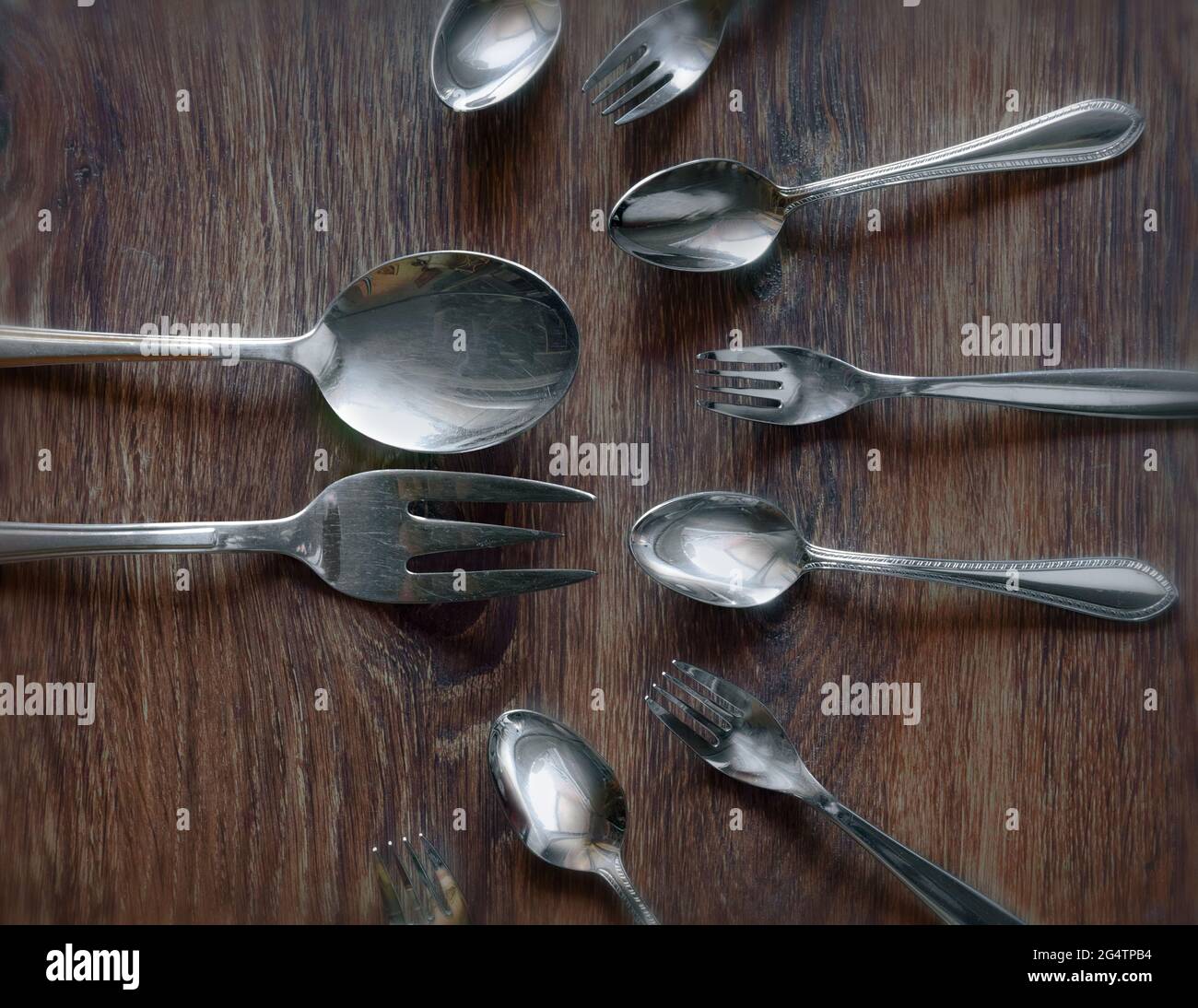 A large spoon and fork surrounded by smaller ones Stock Photo