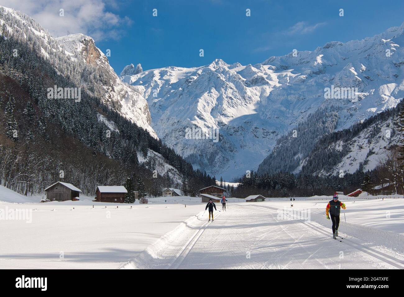 Mountain scenery at Engelberg in Obwalden canton, central Switzerland with distant people langlauf skiing in a flat area between the mountains Stock Photo