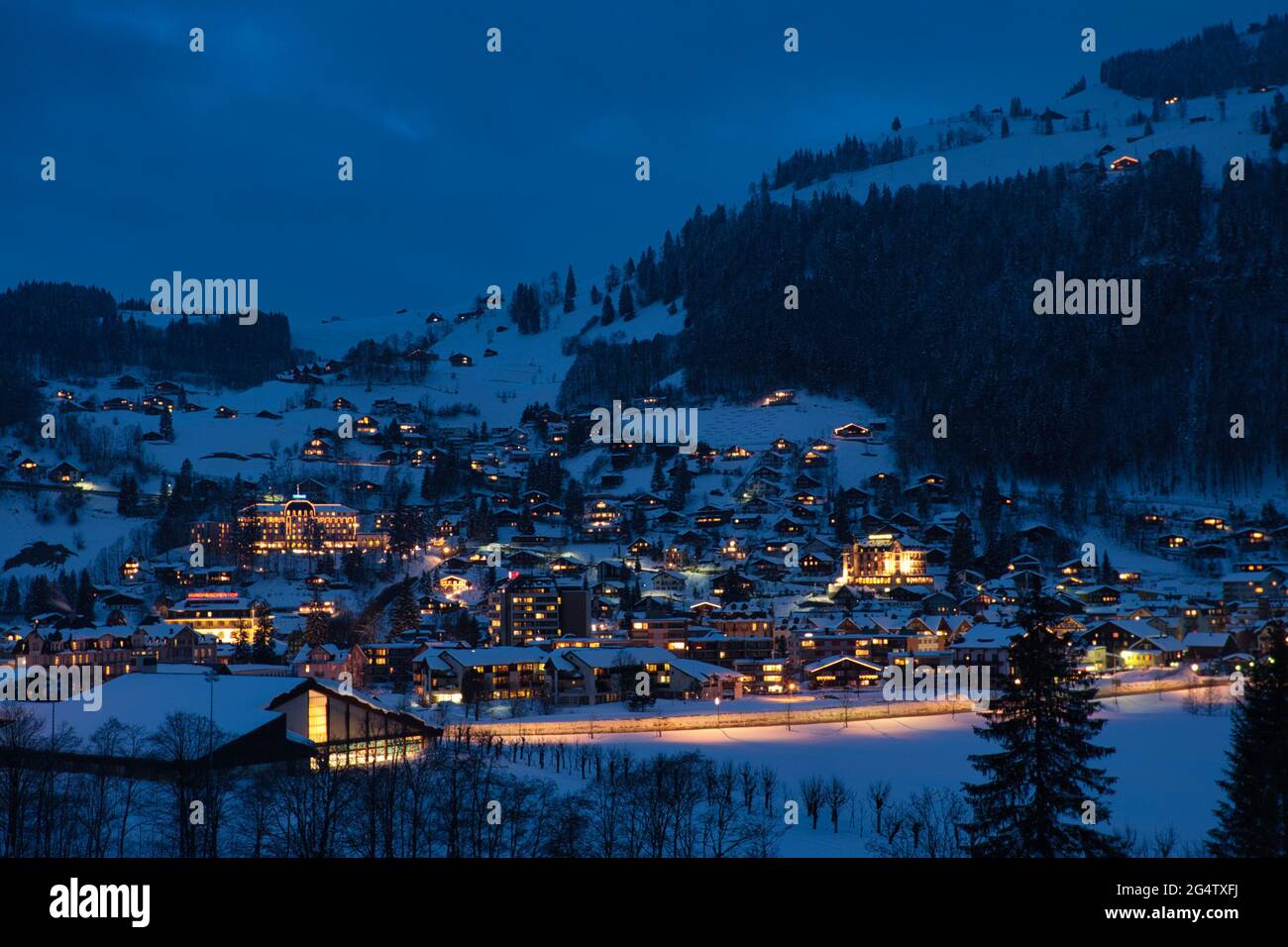 Night time winter landscape view of the snow covered town of Engelberg in Obwalden Canton, central Switzerland, lit up by street lights and houses Stock Photo