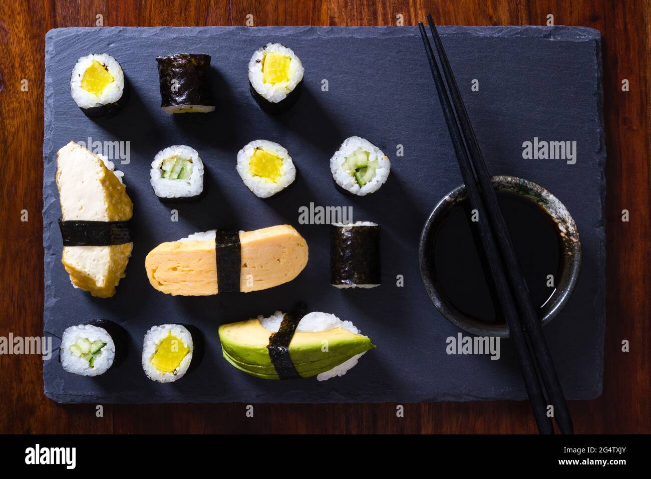 Homemade vegetarian maki and nigiri sushi on slate plate with soy sauce bowl and chopsticks Stock Photo
