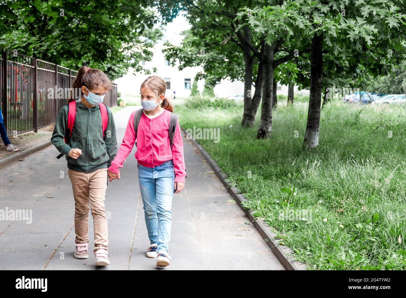Two girls wearing protective face mask and going back to school during ...
