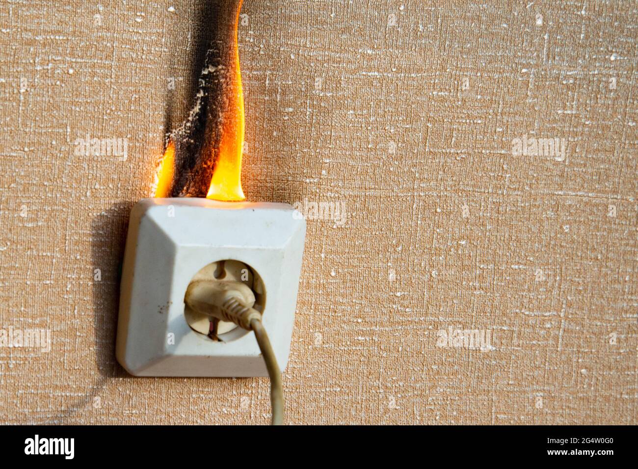 Defective wiring causes a fire. An old, worn out socket requiring replacement. The power outlet starts to light up. Burning electrical wiring and Stock Photo