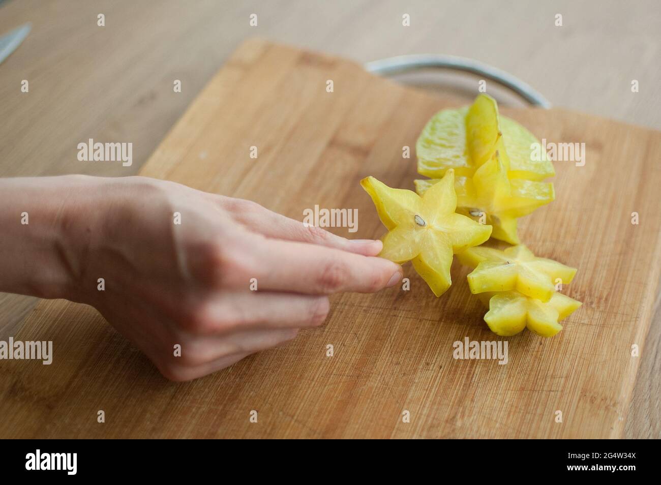 Female hands are holding slice of exotic ripe starfruit or averrhoa carambola. Healthy food, fresh organic star apple fruit Stock Photo