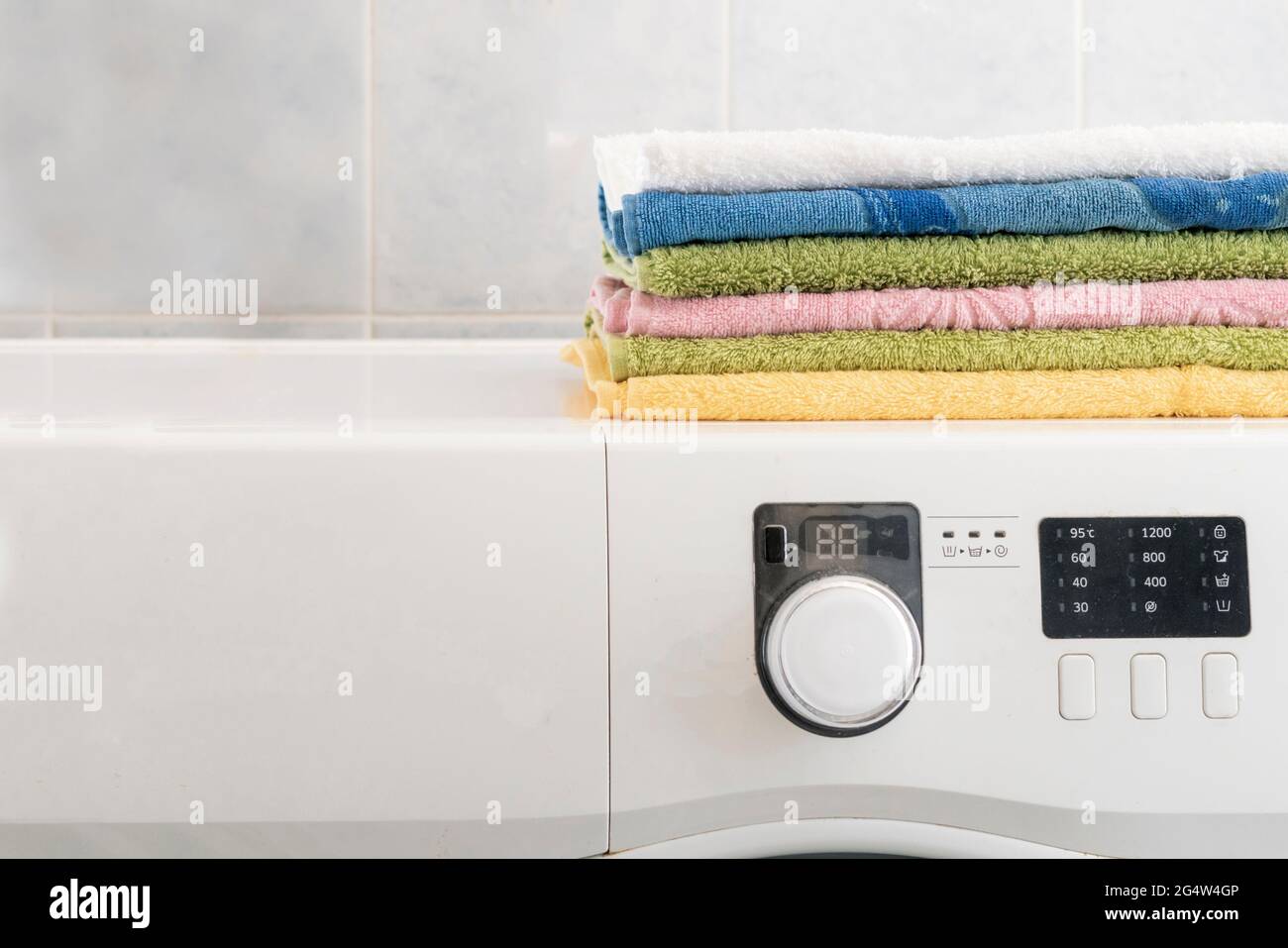 pile of colorful towels lay in the laundry on washing machine and table