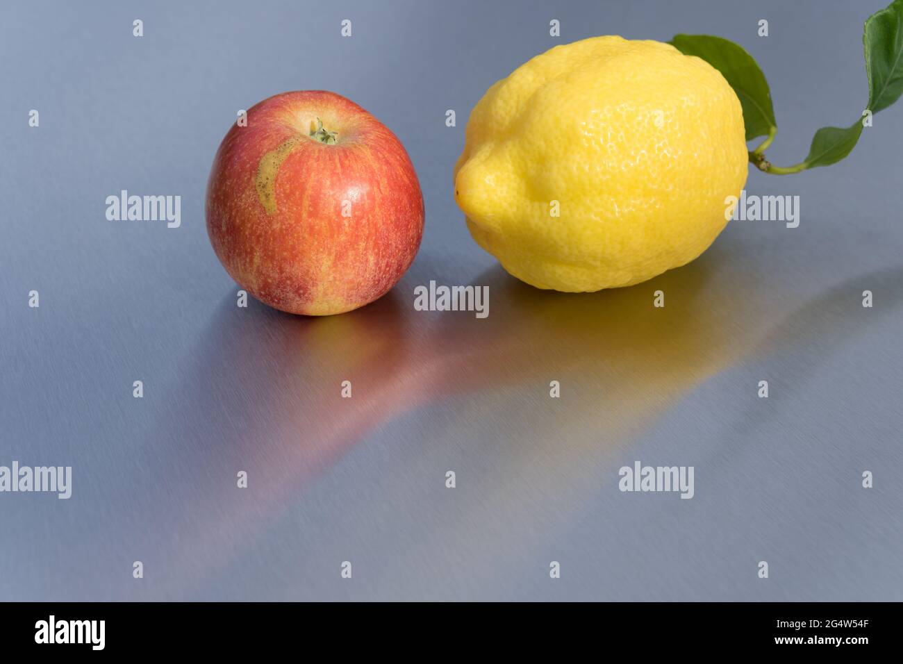 delicious fruits red apple and yellow lemon reflection on clean metallic background Stock Photo
