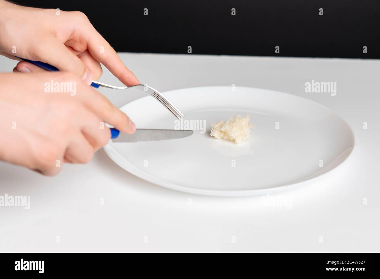 person hands with fork and knife eat small portion of food 