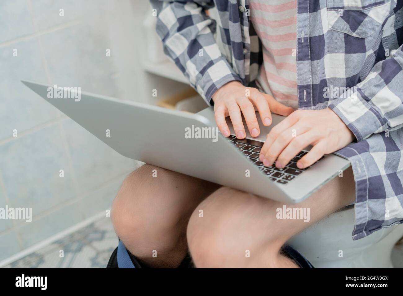 buisnessman sit on toilet and work with laptop in bathroom Stock Photo