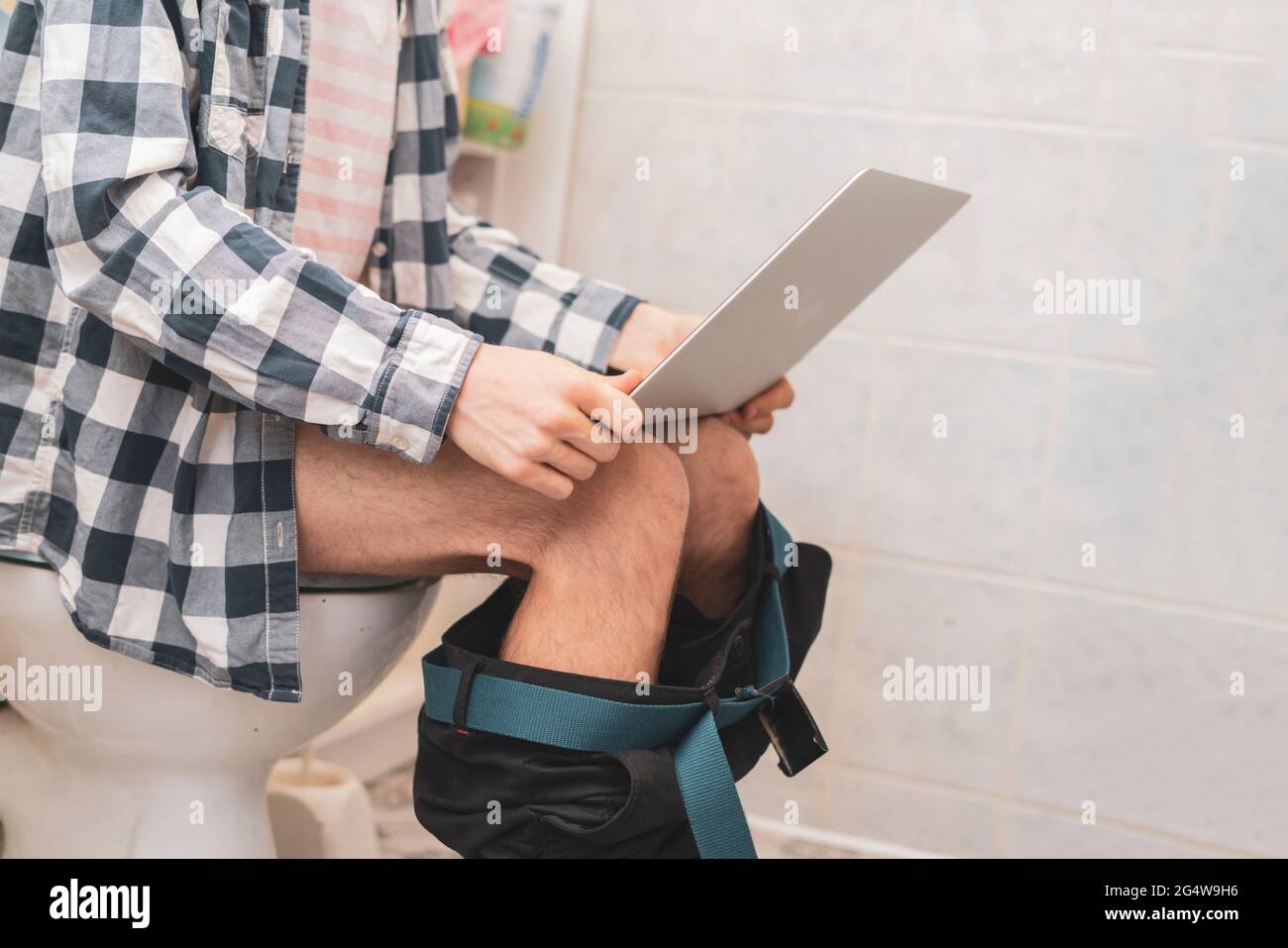 buisnessman sit on toilet and work with laptop in bathroom Stock Photo