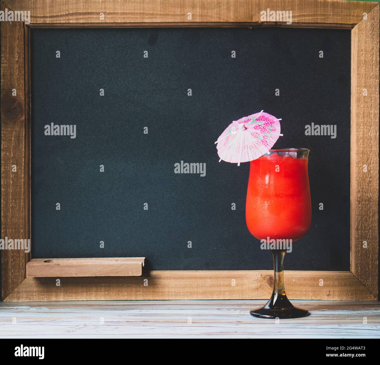 Cocktail drink in front of chalkboard for the drink menu, with tropical wood table Stock Photo