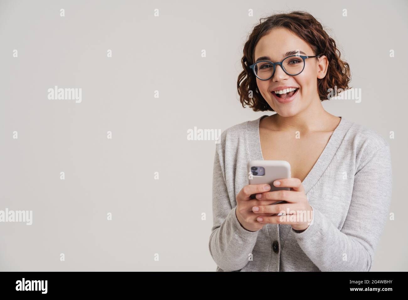 Portrait of an attractive happy young girl in casual clothes using ...