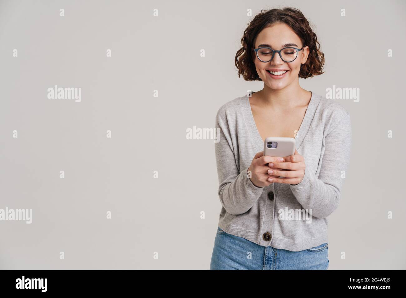 Portrait of an attractive happy young girl in casual clothes using ...