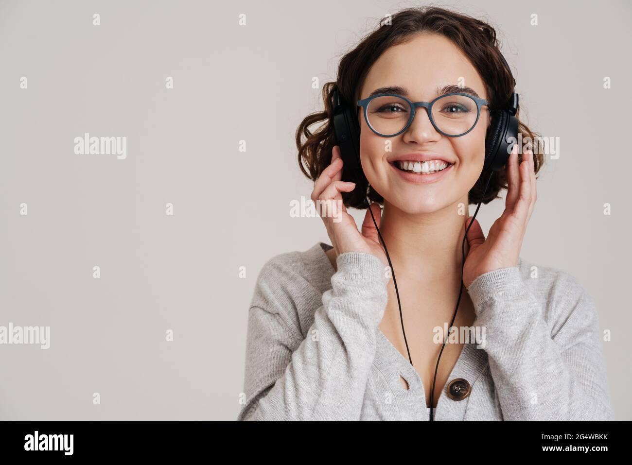 Lovely cheerful young woman listening to music with headphones isolated ...