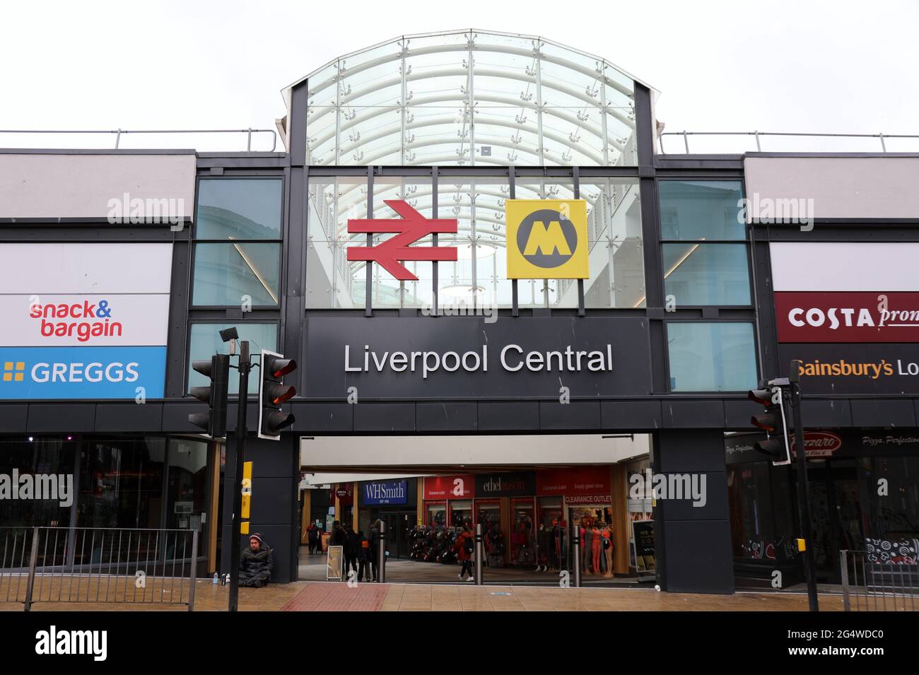 Homeless man sitting in the rain outside Liverpool Central Railway Station Stock Photo