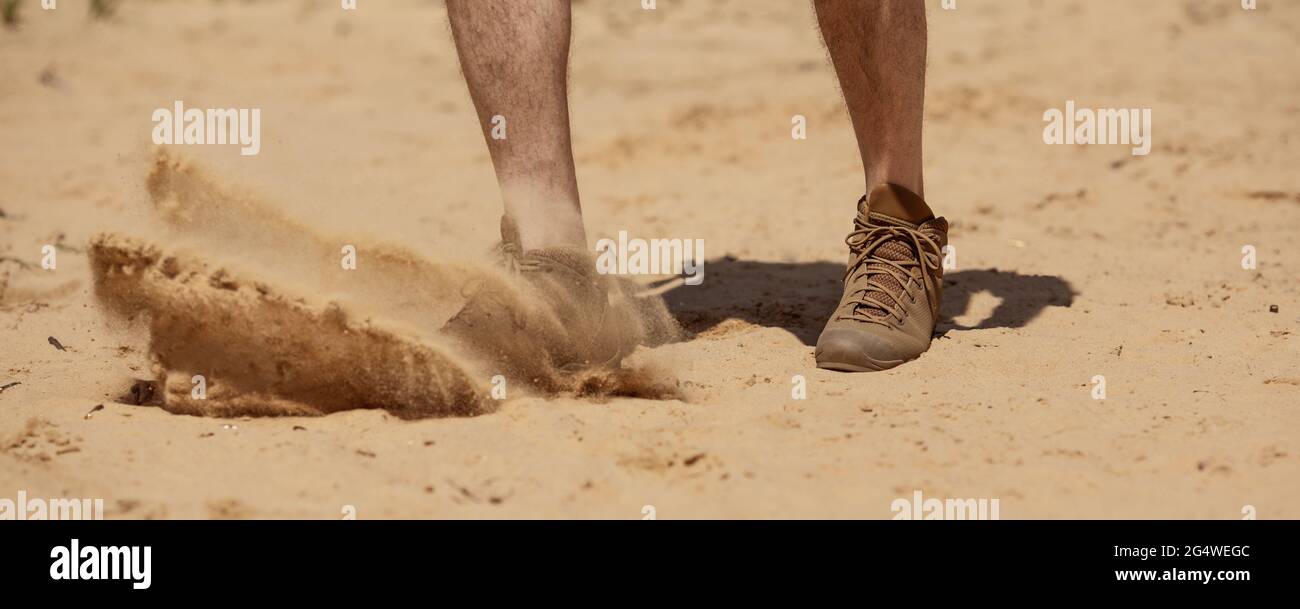 Close up of man legs walking in tactical shoes on sand surface Stock Photo