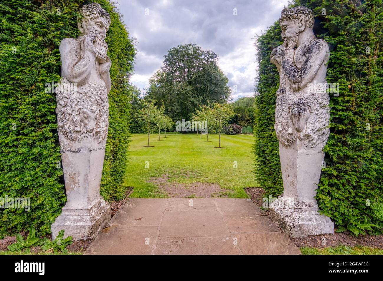Pan piper statues adorn a garden entrance at Anglesey Abbey, a Jacobean-style country house at Lode, near Camdridge, UK, Stock Photo