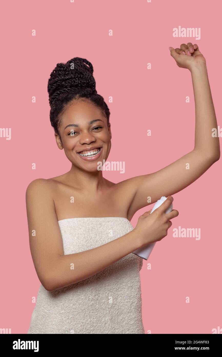 Darkskinned young woman spraying deodorant on her body after shower Stock Photo Alamy