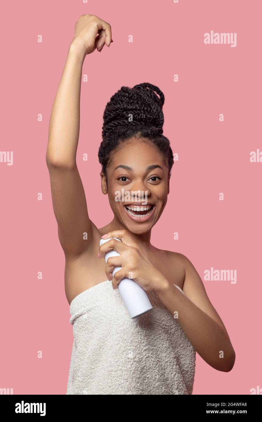 Darkskinned young woman spraying deodorant on her body after shower Stock Photo Alamy