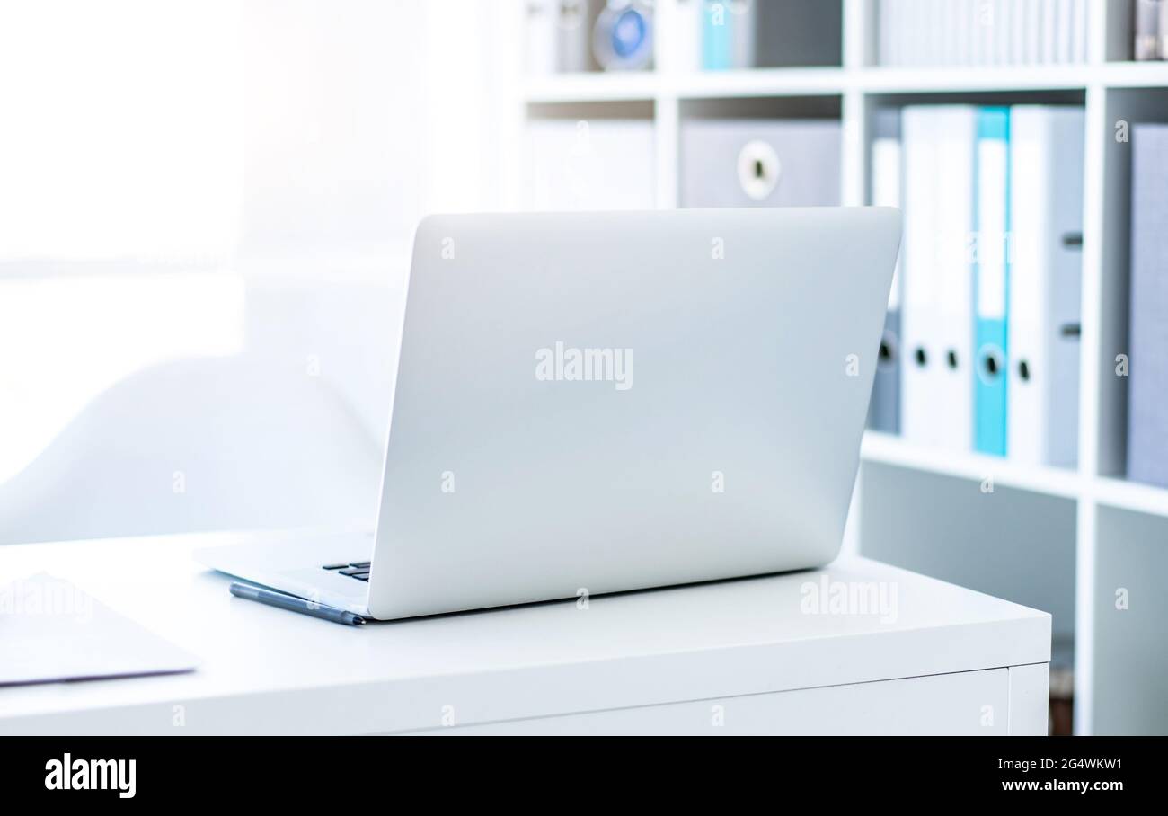Modern laptop on white table in light office Stock Photo