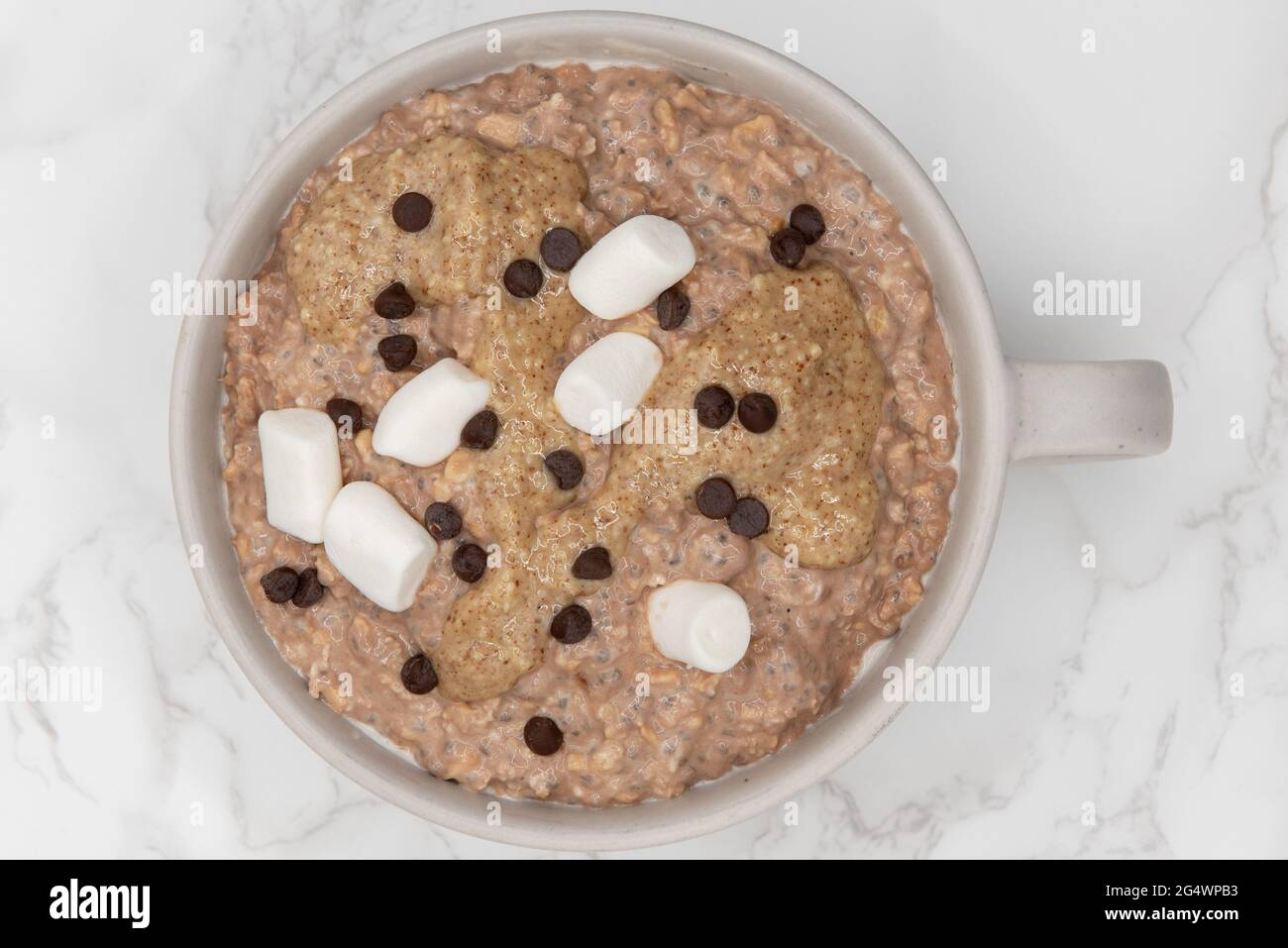 Marshmellows and chocolate chips on top of oatmeal ready to eat in a bowl on the table is a great way to start the day with a good source of fiber and Stock Photo