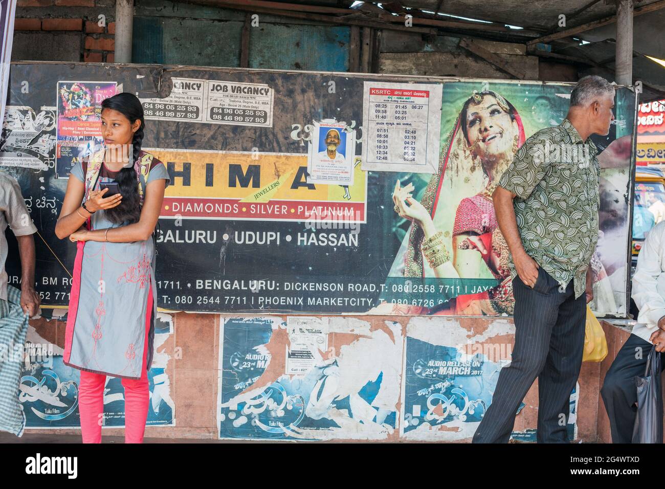 Attractive Indian student wearing salwar kameez stands waiting at bus stop, Udupi, Karnataka, India Stock Photo