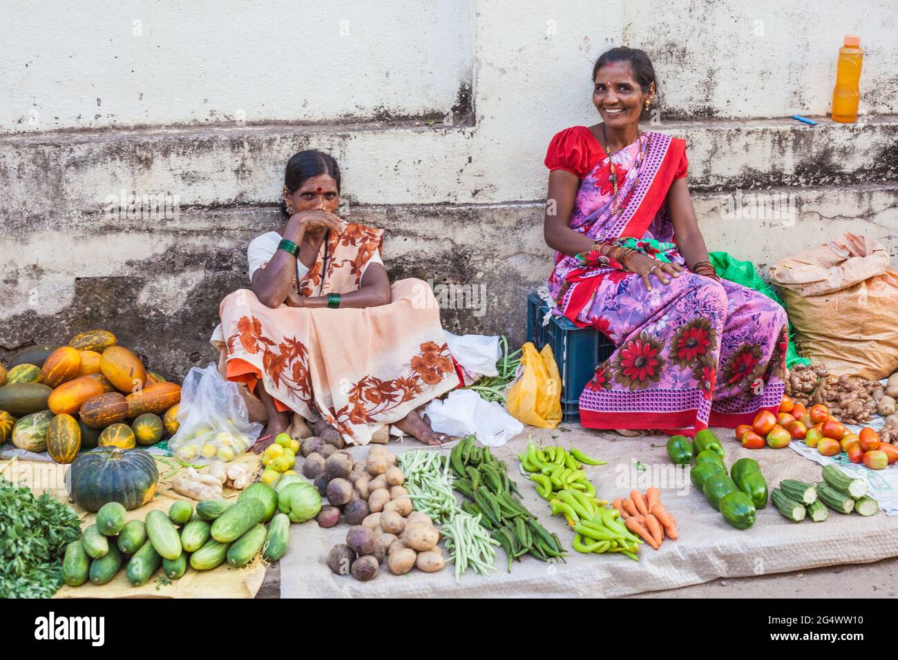 Attractive Indian market traders smiling for camera selling vegetables at their stall, Udupi, Karnataka, India Stock Photo