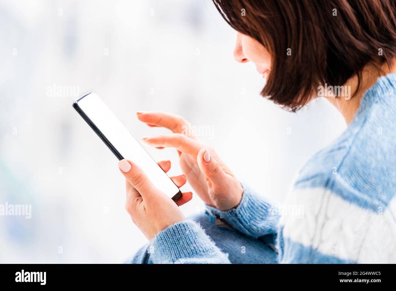 Woman using smartphone in light room Stock Photo