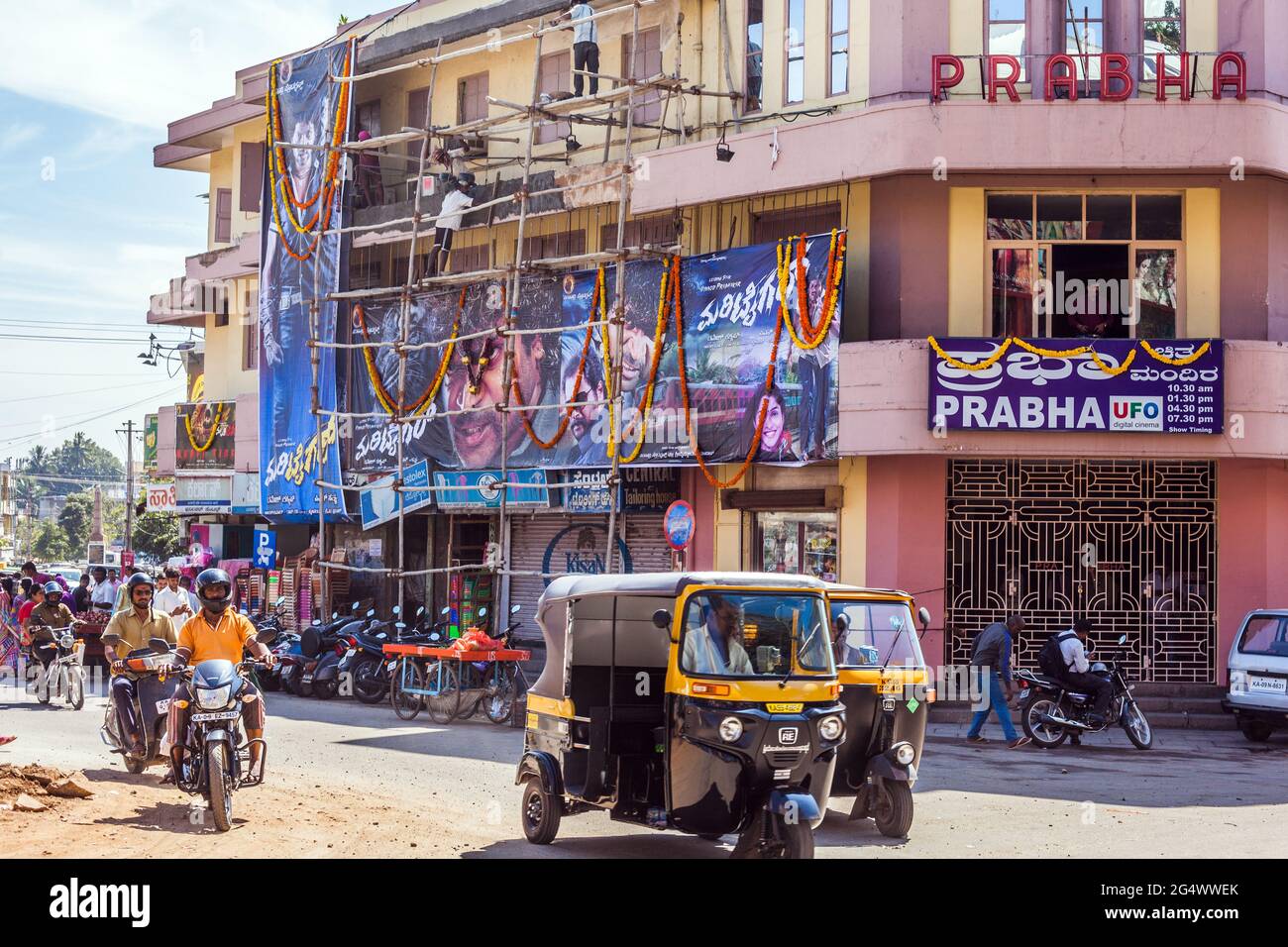 Indian labourers standing on bamboo scaffolding renovating facade of Prabha cinema movie theatre, Mysore, Karnataka, India Stock Photo