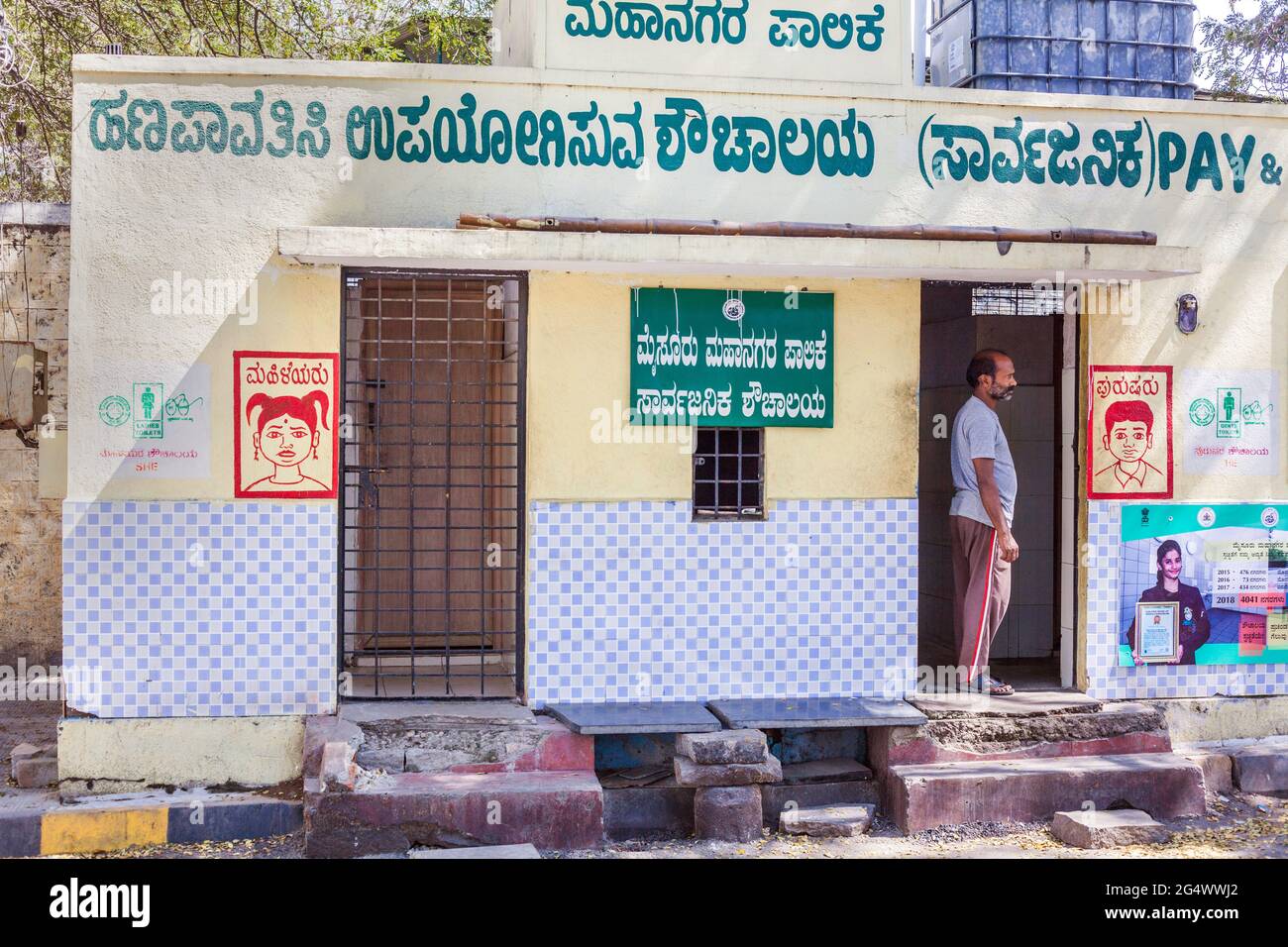 Toilet attendant standing in doorway of public conveniences in Mysore, Karnataka, India Stock Photo