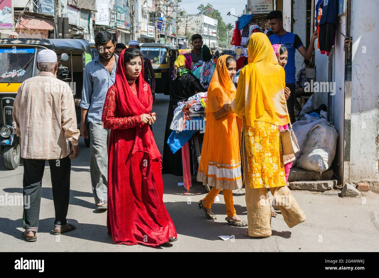 Pretty Indian girl walks mournfully around Muslim area wearing floor length red dress and red headdress , Mysore, Karnataka, India Stock Photo