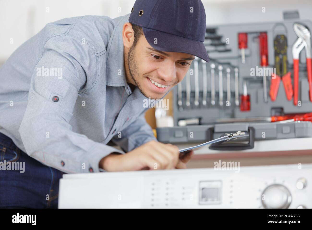 plumber installing washing machine in domestic bathroom Stock Photo