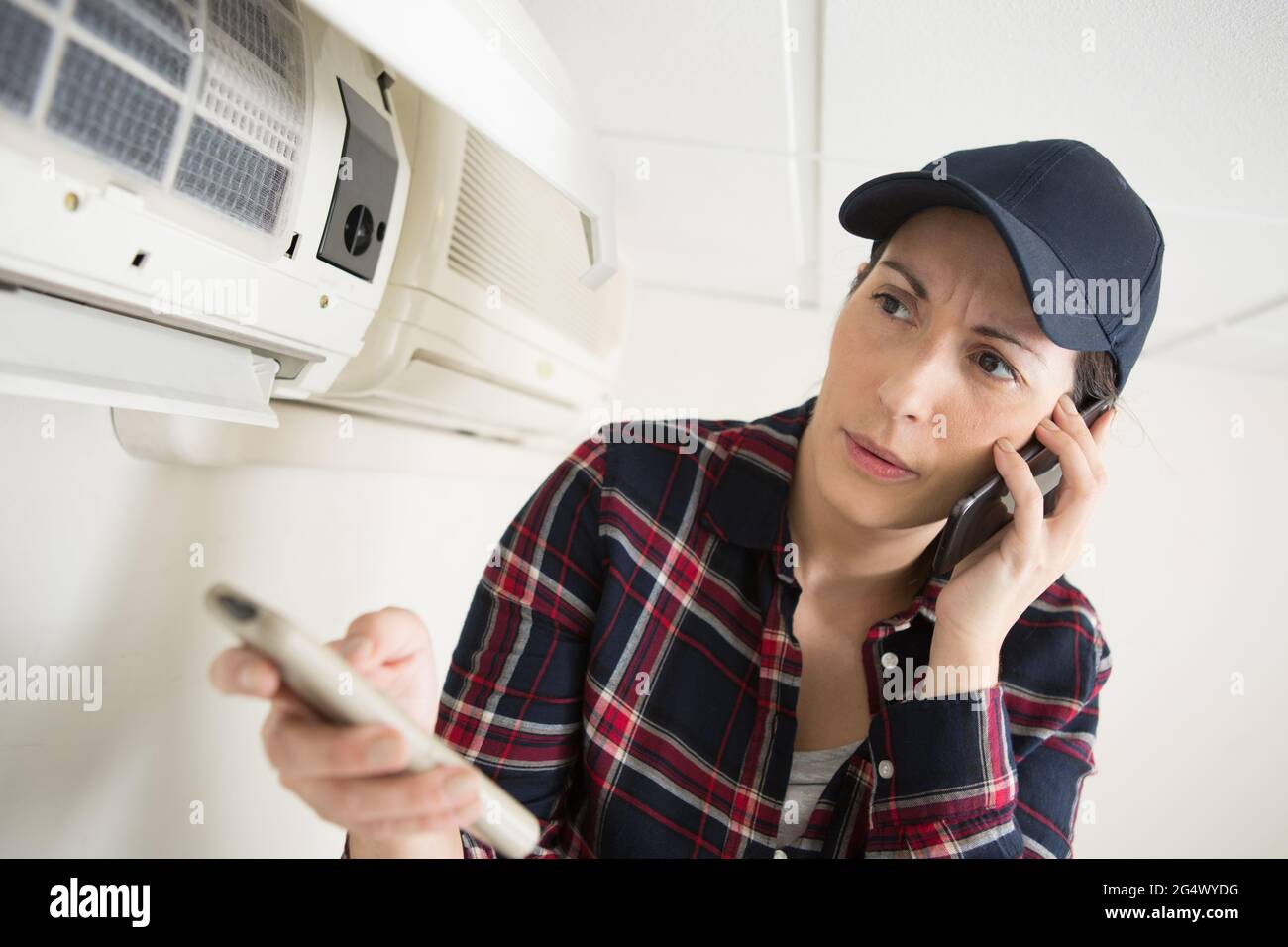 air conditioning engineer holding remote control and talking on